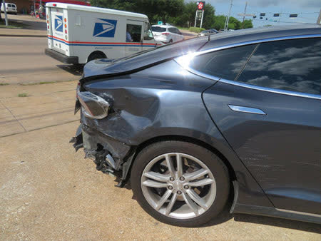 Same Tesla Model S before repair — crushed rear quarter and bumper
